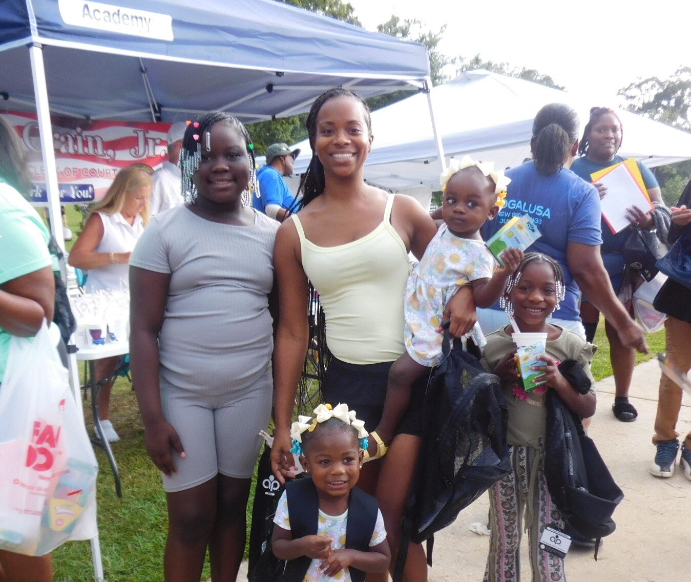 Woman holding a child and smiling with three children next to her