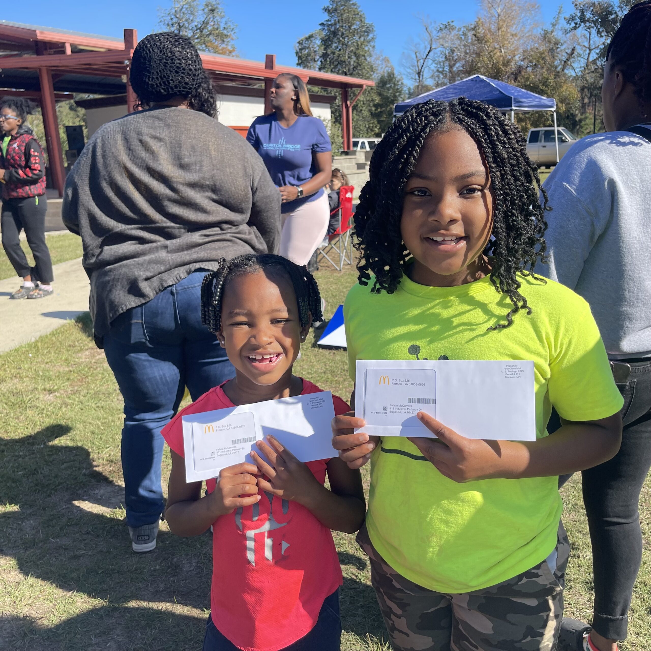 Two smiling children holding up McDonalds gift cards